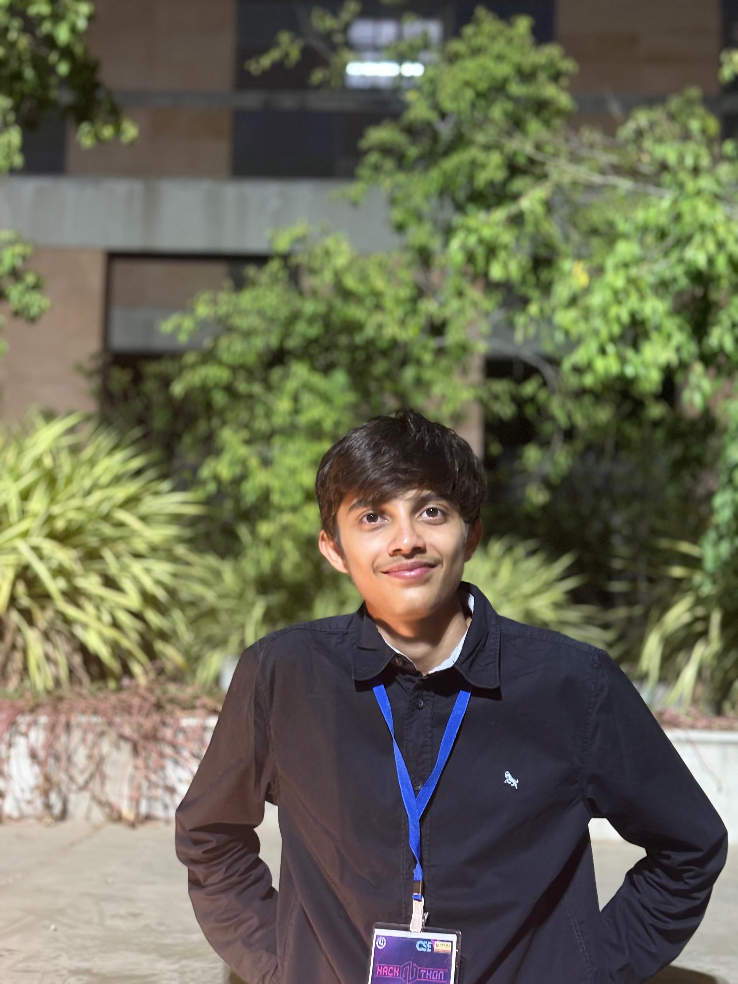 This is Malhar Parikh, a man standing wearing black shirt and smiling